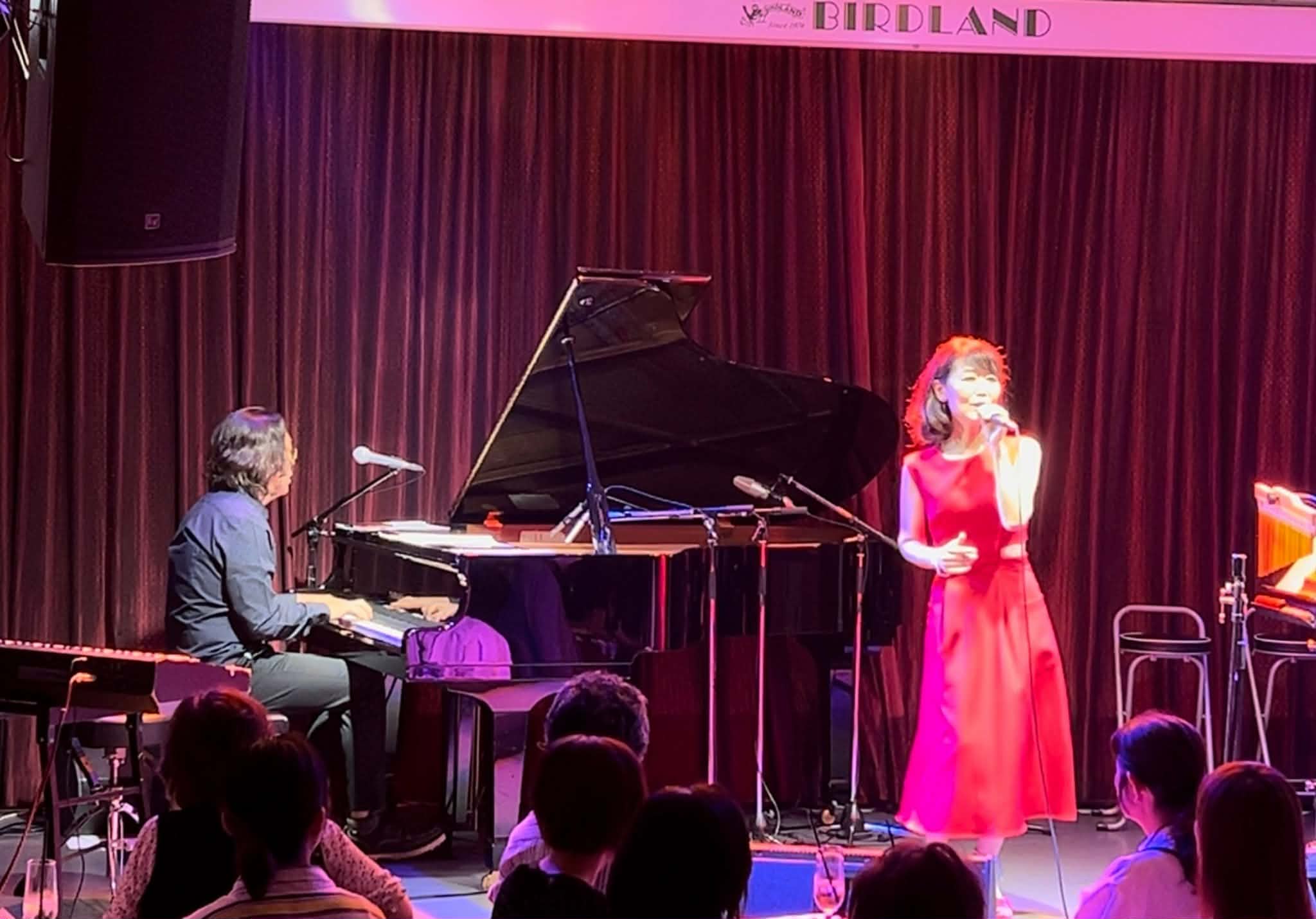 ライブステージで赤いドレスを着て歌う山田ひかる